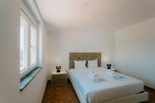 ein weißes Schlafzimmer mit einem großen Bett und einem Fenster in der Unterkunft Best Houses 47 - Consolação Beach House in Atouguia da Baleia
