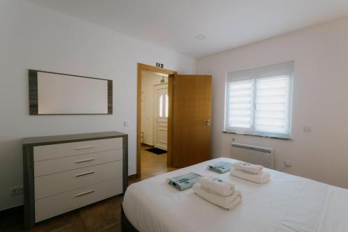 ein Schlafzimmer mit einem Bett mit zwei Handtüchern darauf in der Unterkunft Best Houses 47 - Consolação Beach House in Atouguia da Baleia
