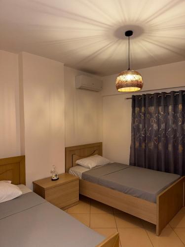 Polisi i VogëlにあるAb apartamentのベッド2台とシャンデリアのある寝室