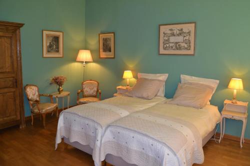 a bedroom with a bed with two chairs and two lamps at Château de la Saulinière in Kain