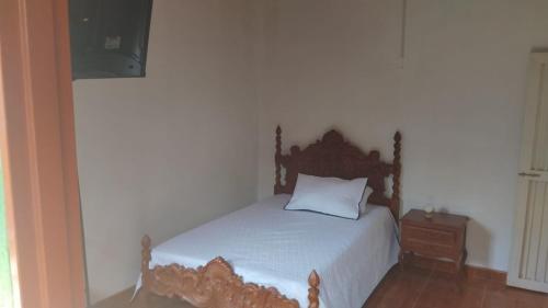 a bedroom with a bed with a wooden headboard and a table at Hostal Villa Laurita in Riofrío