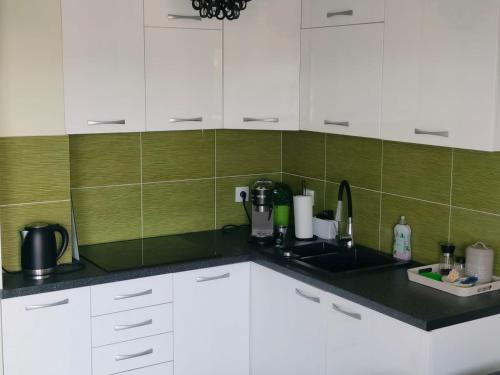 a kitchen with white cabinets and green tiles at Comfy Studio in Rzeszów
