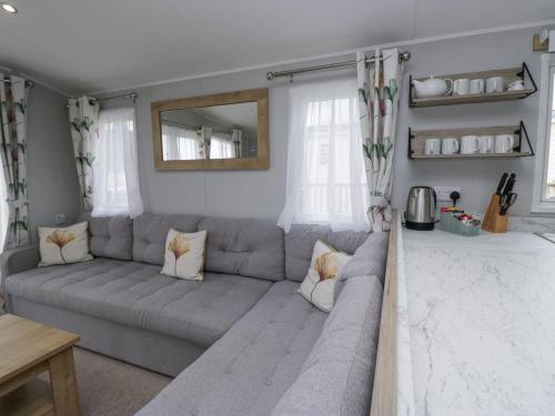 a living room with a gray couch and a mirror at Sandpiper in St Bees