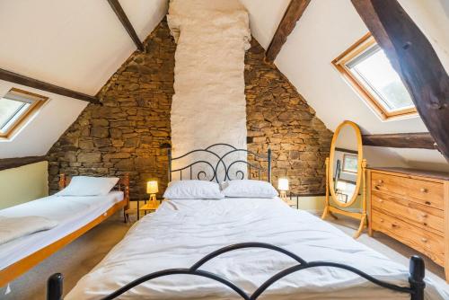 une chambre avec deux lits et un mur en pierre dans l'établissement Moulin de la Touche - Mill Piscine Nature, à Plouguenast Langast