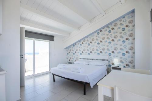 a white bedroom with a bed and a window at Marina di Ragusa residence in Marina di Ragusa