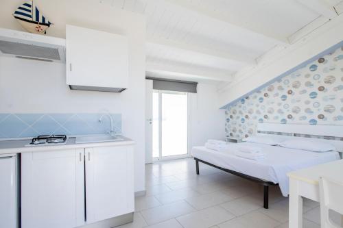 a white kitchen with white cabinets and a table at Marina di Ragusa residence in Marina di Ragusa