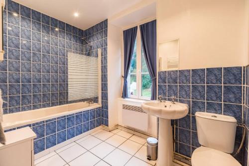 La salle de bains est pourvue de carrelage bleu, de toilettes et d'un lavabo. dans l'établissement Le Moulin de la Touche Minoterie Piscine, à Plouguenast Langast