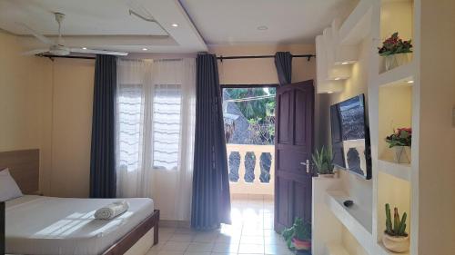 Un dormitorio con una cama y una ventana grande. en Diani Savanna Sunset Studio Apartment, en Diani Beach