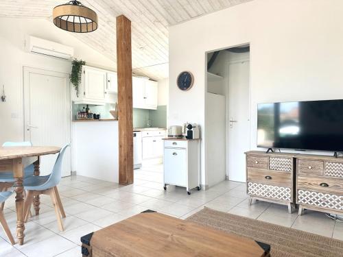 a kitchen with a table and a tv in a room at Maison La Luzala 2 bedrooms beach and port within walking distance in Saint-Pierre-dʼOléron