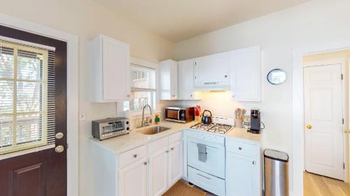 a white kitchen with white cabinets and a sink at MitHarvard, Central Sq, 2 room studio w Porch in Cambridge