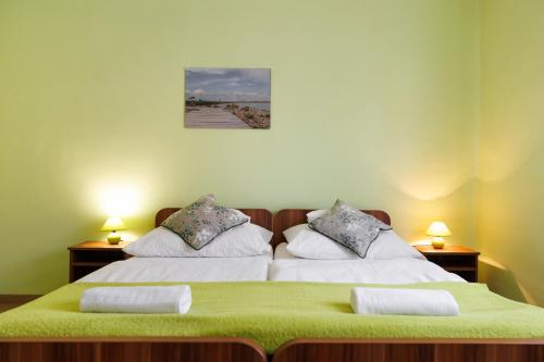 two beds in a room with green sheets and pillows at Lak6 Apartment in Mórahalom