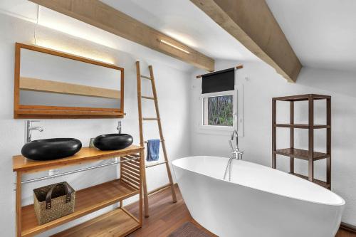 La salle de bains est pourvue d'une grande baignoire blanche et d'un miroir. dans l'établissement Maison de la Fare- plongez en pleine nature, à Carcès