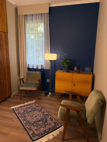 a living room with a chair and a dresser and a window at Fonte Salis Apartman in Egerszalók