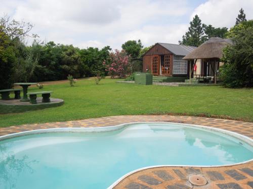 a swimming pool in a yard with a house at Nullarbor Cottages in Magaliesburg