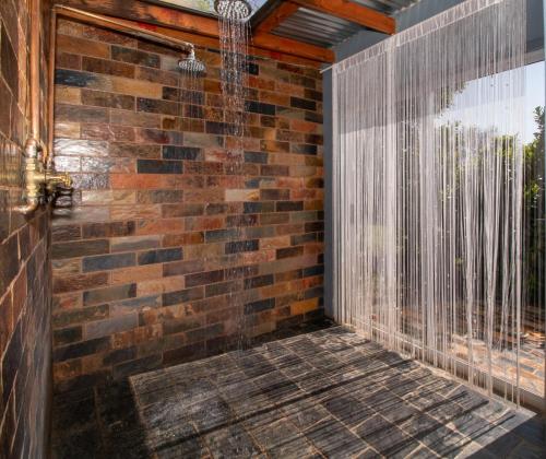 a room with a brick wall and a shower at Nullarbor Cottages in Magaliesburg