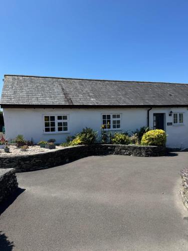 a white house with a driveway in front of it at Titmouse at Trenale Court Cottages in Tintagel