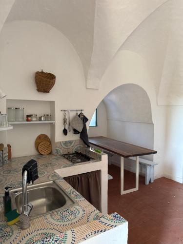 a kitchen with a sink and a counter with a table at Al Palazzotto in Pantelleria