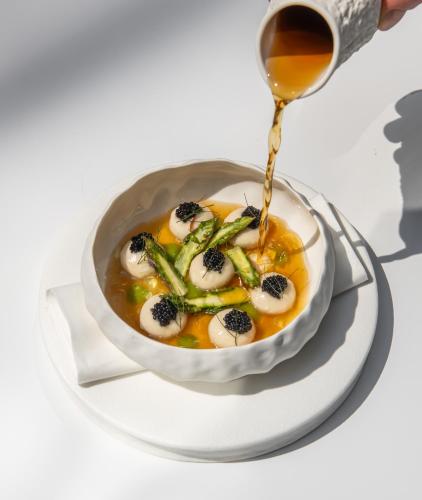 a bowl of soup with cheese and asparagus at Hotel Blow Up Hall in Poznań