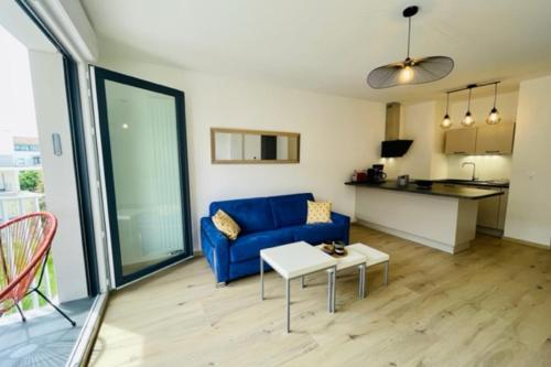 un salon avec un canapé bleu et une table dans l'établissement charming new flat with balcony, à La Rochelle