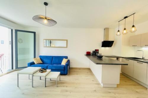 Il comprend une cuisine et un salon doté d'un canapé bleu. dans l'établissement charming new flat with balcony, à La Rochelle