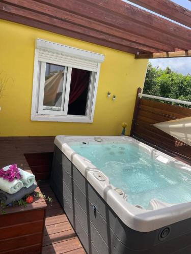 a jacuzzi tub in a backyard with a yellow wall at Maison avec terrasse à Saint-François - 50 m² avec spa in Saint-François