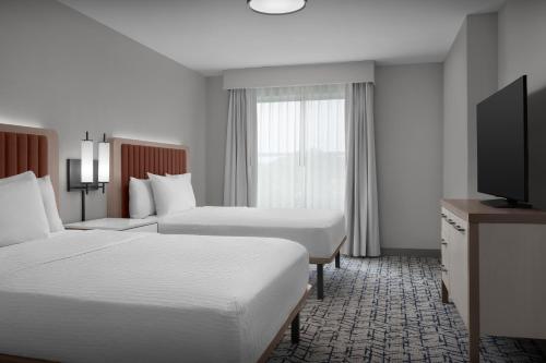 a hotel room with two beds and a flat screen tv at Homewood Suites by Hilton Princeton in Princeton