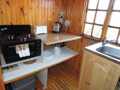 a small kitchen with a stove and a sink at Nullarbor Cottages in Magaliesburg