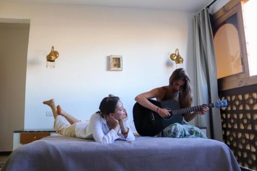 two girls laying on a bed while a woman playing a guitar at Rafiki Oasis in Dahab