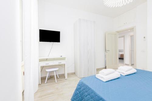 a white bedroom with a blue bed and a desk at Enjoy Apartment - Guest House in Ciampino