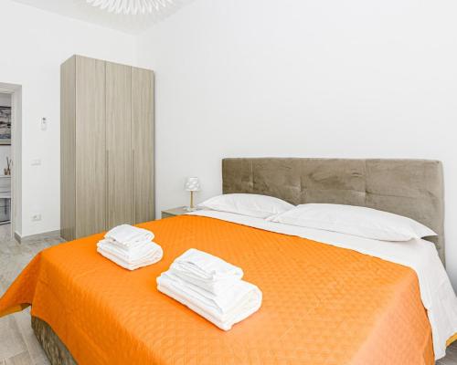a bedroom with an orange bed with towels on it at Enjoy Apartment - Guest House in Ciampino