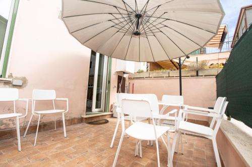 a patio with white chairs and an umbrella at Enjoy Apartment - Guest House in Ciampino