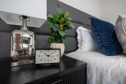 a clock sitting on a table next to a bed at 3BR3Bth Penthouse 2 Parking Spaces TD MIT Harvard in Somerville