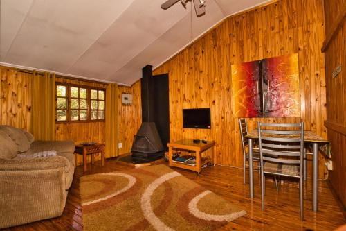 a living room with a couch and a table and a fireplace at Nullarbor Cottages in Magaliesburg