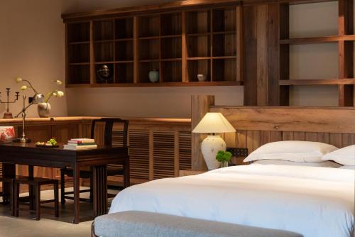 una camera da letto con un letto, un tavolo e una scrivania di Ethnic Hundred-years Elysian Culture&Art Scholar Resorts a Zhangjiajie