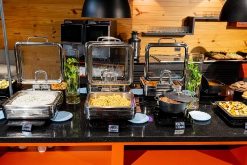 a buffet with several trays of food on a counter at Ibis Budget Guarulhos Aeroporto in Guarulhos