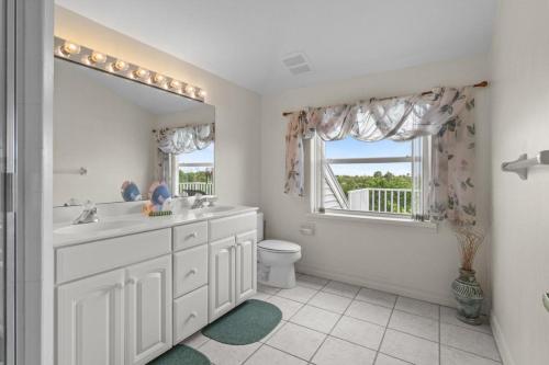 a bathroom with a sink and a toilet and a mirror at Halliday in Sanibel