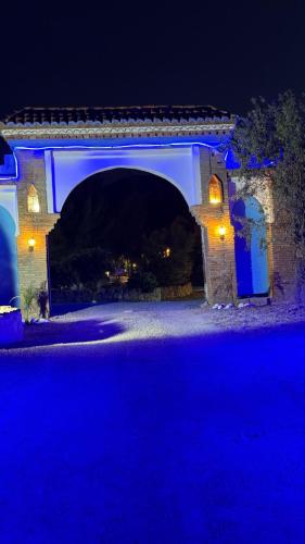 a stone archway with a blue lighted bridge at night at Auberge Alwahabi in Chefchaouene