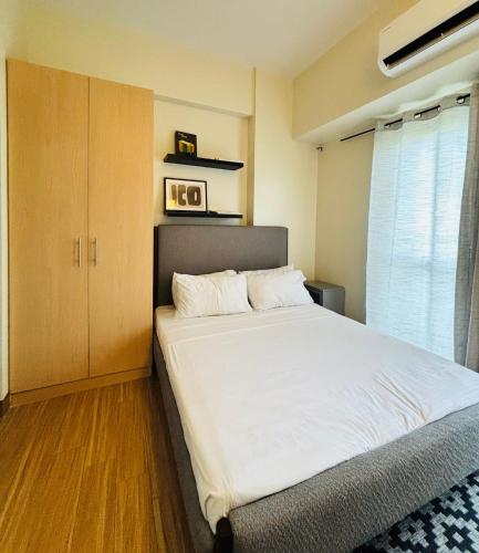 1 dormitorio con 1 cama blanca y armario en Nature Lovers Paradise in Iloilo City - Cozy Condo Rental, en Iloilo City