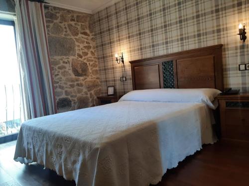 a bedroom with a bed and a stone wall at Hotel GBC Celta in A Guarda