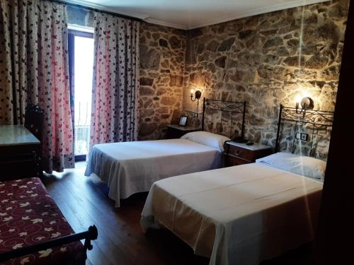 a bedroom with two beds and a stone wall at Hotel GBC Celta in A Guarda