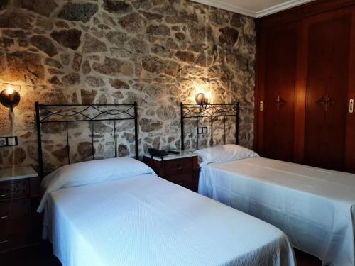 two beds in a room with a stone wall at Hotel GBC Celta in A Guarda