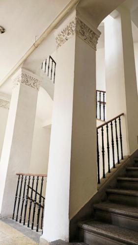 a staircase in a building with white walls and columns at Fountain Residence in Sopron