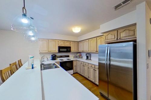 a kitchen with wooden cabinets and a stainless steel refrigerator at Salt Pond --- 38435 Mainsail Dr #9 in Bethany Beach