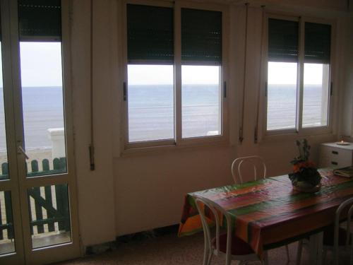 a dining room with a table and chairs and windows at Casa sulla spiaggia davanti al mare in Follonica