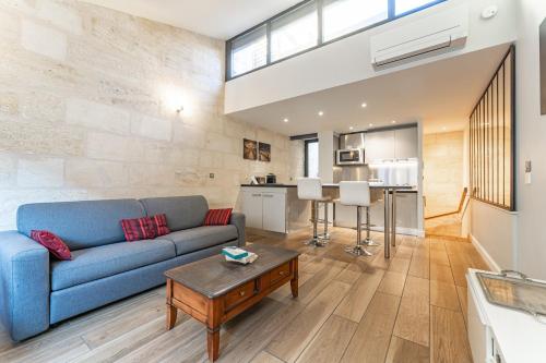 a living room with a blue couch and a table at Superbe Duplex en Hypercentre avec Rooftop et Climatisation in Bordeaux