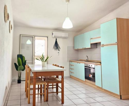 a kitchen with blue cabinets and a table and chairs at Bentos - Appartamenti in centro a Orosei in Orosei