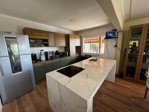 a kitchen with a marble counter top and a refrigerator at Chácara Cascavel em Gravatá in Gravatá