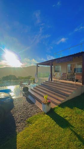 a house with a deck and a house with the sun at Chácara Cascavel em Gravatá in Gravatá