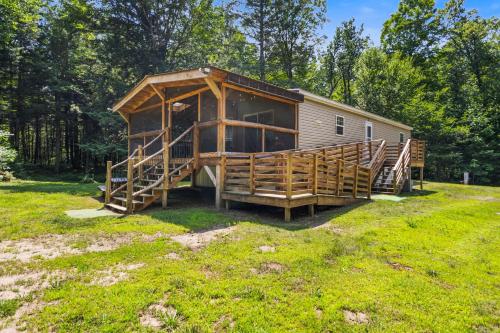 a cabin with a large deck in the grass at Schroon River Bend Getaway in Schroon Lake