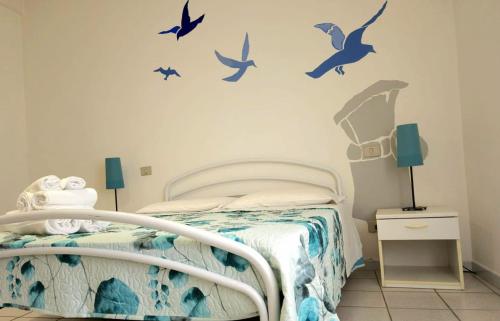 a bedroom with a bed with birds on the wall at Bentos - Appartamenti in centro a Orosei in Orosei